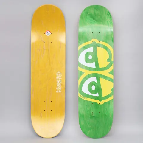 Krooked Team Eyes Yellow skateboard deck: A large pair of cartoon eyes in yellow and white sits on a green-stained deck. The brand's handwritten name is at the bottom left, with a yellow-stained underside shown beside it.