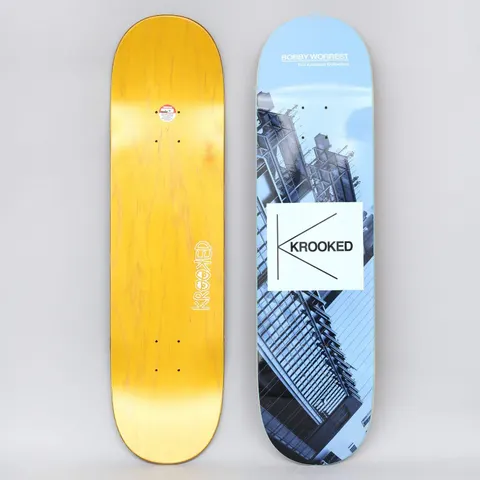 Krooked Worrest Kollection Full Blue skateboard deck: Blue-tinted photograph of a modern glass and steel building on a tilted angle, with a white square carrying the Krooked K logo. Rider name and 'The Krooked Kollection' are printed at the top. Photo shows both the graphic and the yellow bottom.