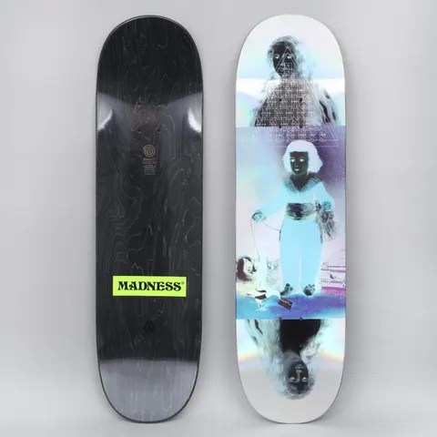 Madness Manvel Infant Holographic skateboard deck: A colour-inverted image of a child in a robe leading a small dog on a lead, with a bird cage beside them, and a ghostly dark face above and mirrored below. A triangle of repeating 'Madness' text sits in between on a holographic deck.