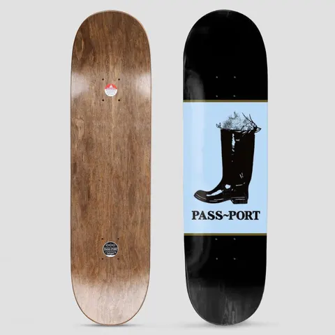 Passport Shoe Series Welly skateboard deck: Black wellington boot with plants growing from the top, on a pale blue panel with a gold border across a black deck. Brand name in serif capitals below. Brown stained underside shown alongside.