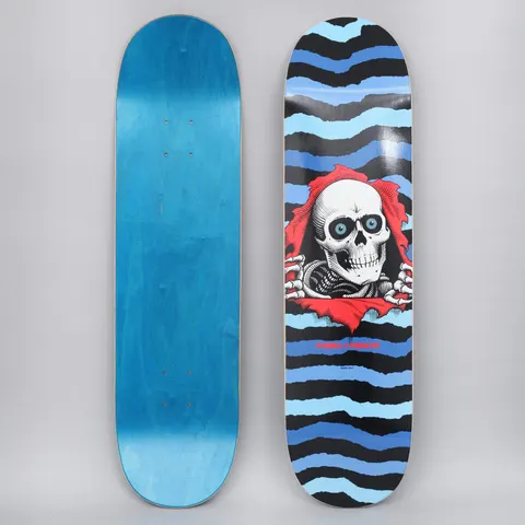 Powell Peralta Peralta 8.25 Ripper Shape 243 Blue skateboard deck: The Ripper skull bursting through torn red paper, with skeletal hands gripping the tear, set against jagged horizontal stripes in blues and black. Powell Peralta name in red beneath.