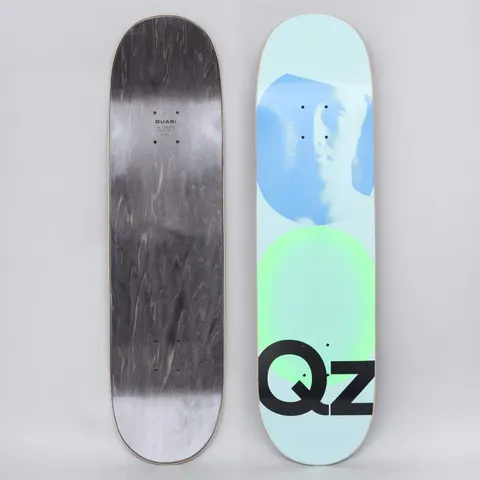 Quasi Quasi 8.25 QZ 101 Blue skateboard deck: A pale blue deck with a blue halftone profile of a face in a circle above a green glowing circle, with a large black QZ lettering at the bottom. The underside is black-stained with small Quasi text.