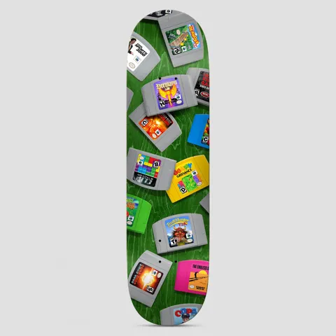 Real Hermann 64 Bit True Fit skateboard deck: Spilled grey, coloured and neon Nintendo 64 style game cartridges lie scattered across a green wood-grain ground. The cartridge labels have invented game titles.