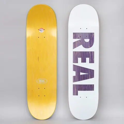 Real Bold Series White skateboard deck: Large bold block letters spelling REAL cut out of a white top, showing the purple-stained wood beneath. The underside is yellow with a small oval Real logo.