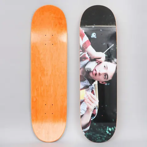 Skateboard Cafe Day Off Black skateboard deck: A colour film still of a teenage boy in a striped shirt holding a large early mobile phone to his ear and a glass of orange juice, cropped sideways against a dark leafy background.