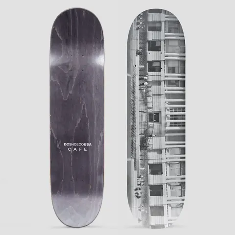 Skateboard Cafe x DC Shoes 8.0 Lloyds Photo Grey skateboard deck: A black and white photograph of a building facade with rows of windows, columns and a fire escape, with a few tiny figures along it. The photo also shows the grey underside with DC Shoe Co USA Cafe text.