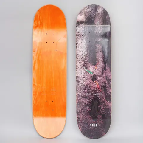 Sour Simon Worms skateboard deck: Close photograph of a gnarled, purplish-brown tree trunk with three small gummy worms crawling across the bark. Small credit text sits mid-board and the brand name is printed near the tail.