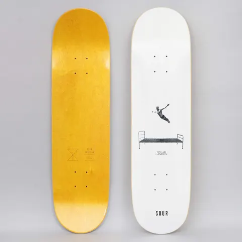 Sour Oscar Bed Of Nails White skateboard deck: Minimal white deck with a small photo cut-out of a figure diving through the air above a metal bed frame with a bed of nails, with a name and the SOUR wordmark below. The underside is yellow-stained.