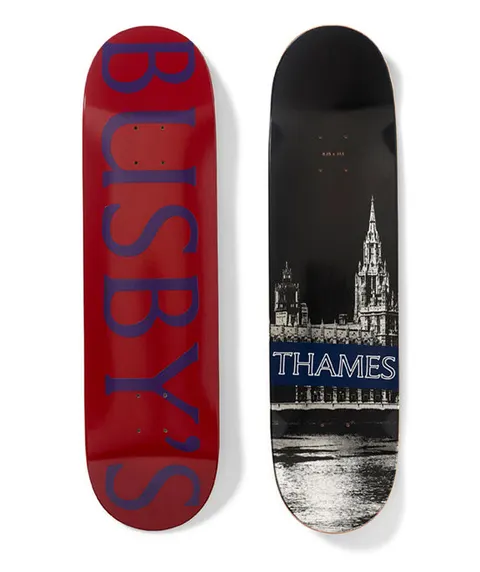 Thames MMXX Busbys Board skateboard deck: One side is a red deck with large blue serif lettering reading Busby's down its length. The other is a black and white photo of the Houses of Parliament and the river, with a navy banner reading Thames.