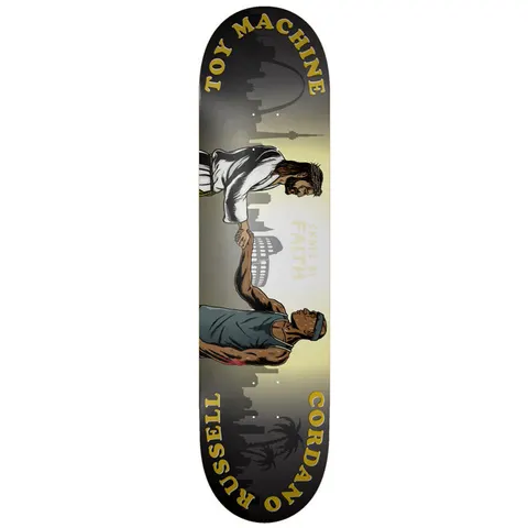 Toy Machine Cordano Russell Skate By Faith 8.50 skateboard deck: Illustration of a robed, bearded Jesus-like figure shaking hands with a muscular man in a vest and headband, against a faded skyline with the Colosseum and palm trees. Gold curved text names Toy Machine, Cordano and Russell.