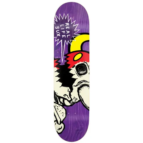 Toy Machine Real Life Sux 8.25 skateboard deck: A cream cartoon monster face with a red cap, yellow horn and a black eye socket is cropped on the deck, with a jagged white speech bubble reading REAL LIFE SUX on a purple stained deck.
