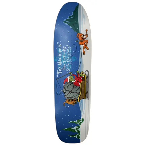 Toy Machine Turtle Boy Stole X - Mas 8.75 skateboard deck: Parody of a Christmas story: a green Turtle Boy in a Santa suit on a sleigh pulled by orange Toy Machine creatures through a snowy night landscape, with the title in white text on a blue shaped deck.
