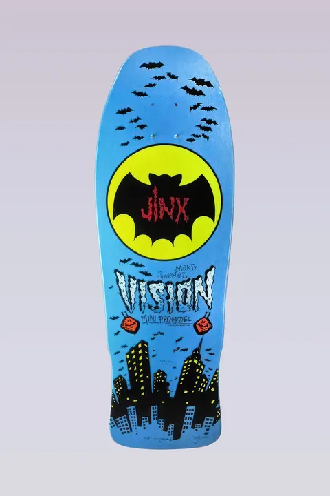 Vision Street Wear Jinx - Mini Modern Concave - Blue skateboard deck: Yellow bat-signal circle holding a black bat with Jinx in red lettering, surrounded by swarming bats above a black city skyline. Hand-drawn Vision lettering with Marty Jimenez and Mini Pro Model on a metallic blue deck.