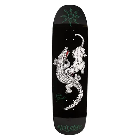 Welcome Jake Yanko Swamp Fight on Panther - White/Black - 9.0 skateboard deck: A white-line illustrated crocodile and a panther locked in a fight, with a red mouth on the croc, on a black shaped deck. A green tribal sun motif sits at the nose and green lettering at the tail.