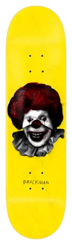 Zero Iconoclash - Brockman skateboard deck: Greyscale photographic-style image of a grinning clown with a red wig, red nose and ruffled collar, in a fast-food mascot style, on a plain yellow deck. Rider surname in small handwritten type below.