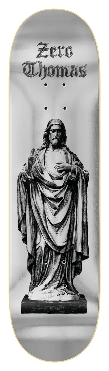 Zero Thomas - Jesus Statue skateboard deck: Black and white engraving-style illustration of a robed statue of Jesus with raised hand, standing on a plinth against a silver foil background. Gothic blackletter 'Zero Thomas' sits at the top.