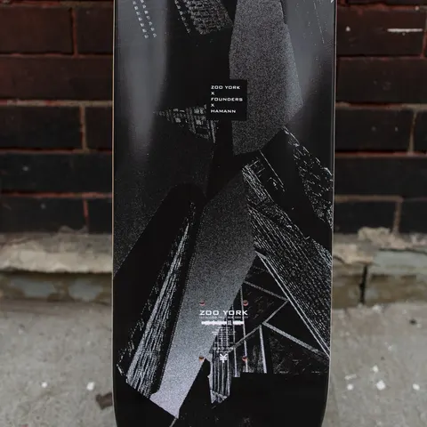 Zoo York Hamann skateboard deck: Black and grey halftone collage of skyscrapers photographed from below, with a small black label at the top naming the collaboration and the Zoo York logo near the tail.