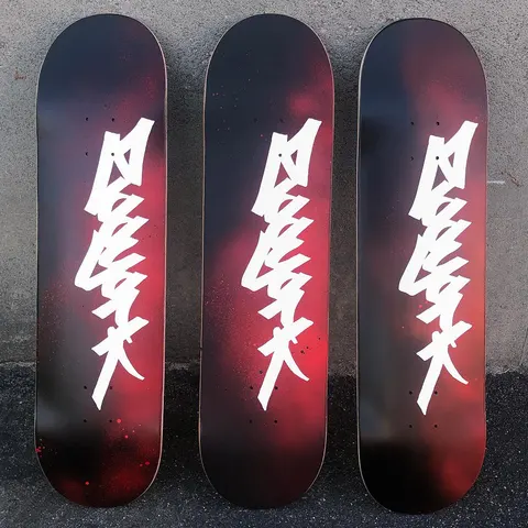 Zoo York Tag skateboard deck: Large white graffiti-style tag lettering running vertically down the deck over a black to red spray-paint fade. Three identical decks are shown side by side.