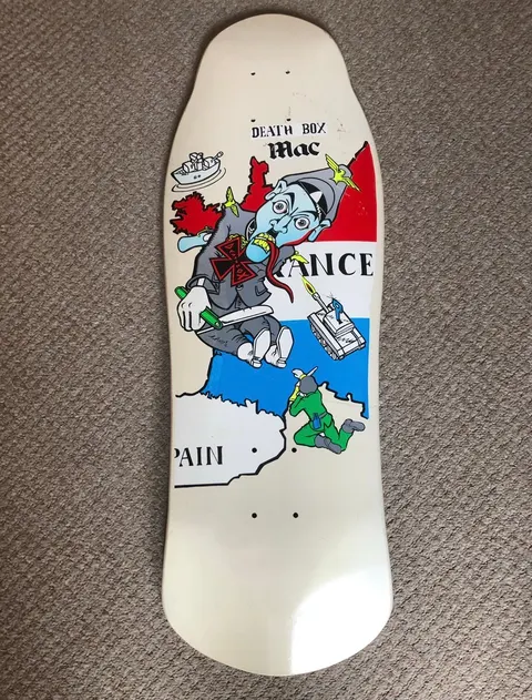 Deathbox World War (White) skateboard deck: Cartoon dictator in a grey uniform with a swastika-style armband breaking out of a map, biting a red-yellow bird and holding a knife, with soldiers and a tank over a French tricolour. Shaped white deck.