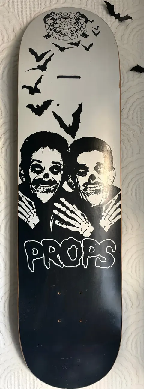 Props skate store Chuckle brothers skateboard deck: Two skeleton-faced figures with painted skull make-up and bony hands on their shoulders, with bats flying above, in black and white horror-punk style. A small circular crest sits at the top and the PROPS logo in dripping letters below.